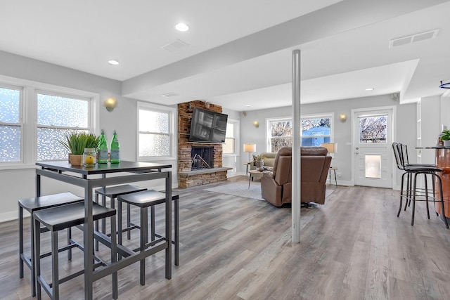 dining area featuring plenty of natural light, visible vents, and a stone fireplace