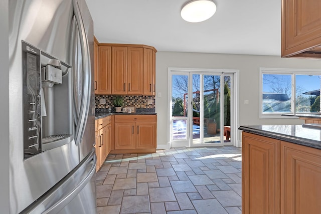 kitchen featuring stone finish flooring, stainless steel fridge, plenty of natural light, and decorative backsplash