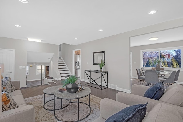 living area with a healthy amount of sunlight, stairs, visible vents, and wood finished floors