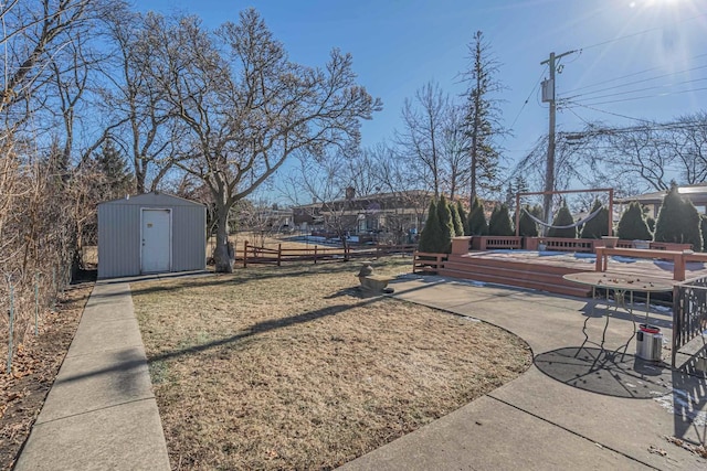 view of yard featuring fence, a storage unit, and an outbuilding