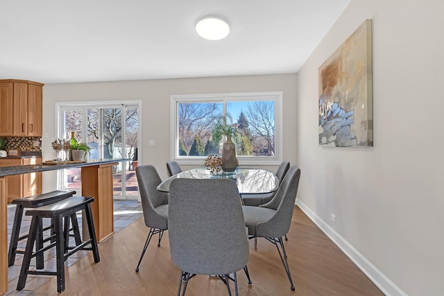 dining space featuring light wood-style flooring and baseboards