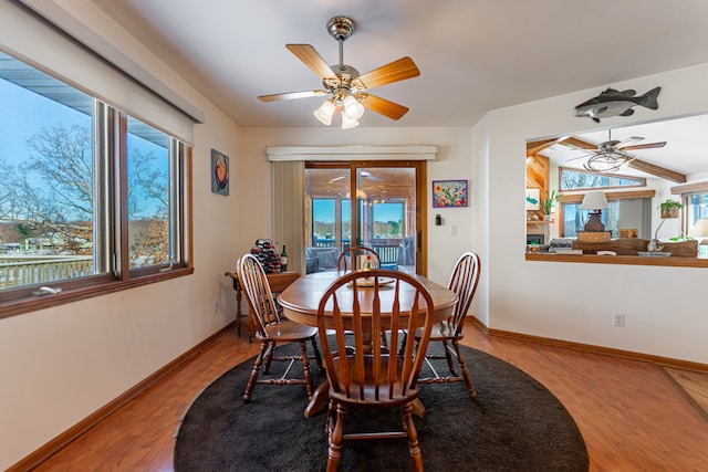 dining area with lofted ceiling, wood finished floors, a ceiling fan, and baseboards