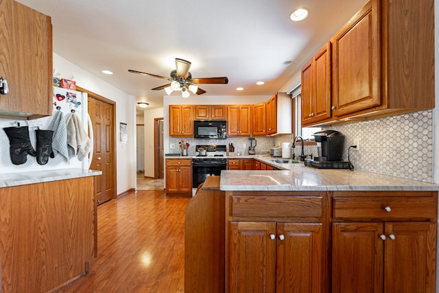 kitchen with range with gas cooktop, light countertops, brown cabinetry, a sink, and black microwave