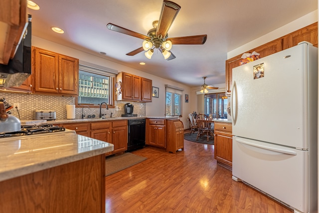 kitchen featuring decorative backsplash, freestanding refrigerator, light wood-type flooring, dishwasher, and a peninsula