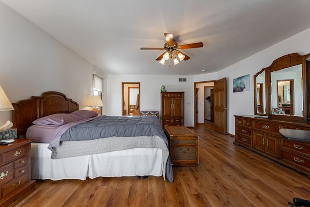 bedroom featuring a ceiling fan, visible vents, and wood finished floors