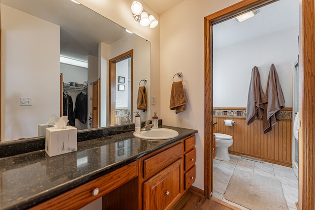 full bathroom featuring visible vents, wainscoting, toilet, vanity, and wood walls