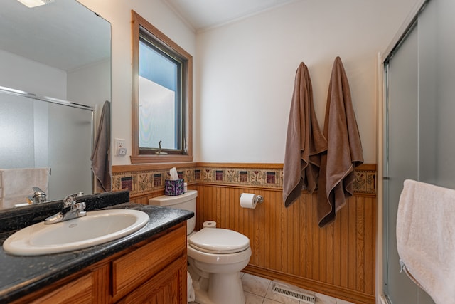 bathroom with a wainscoted wall, visible vents, toilet, a stall shower, and tile patterned flooring