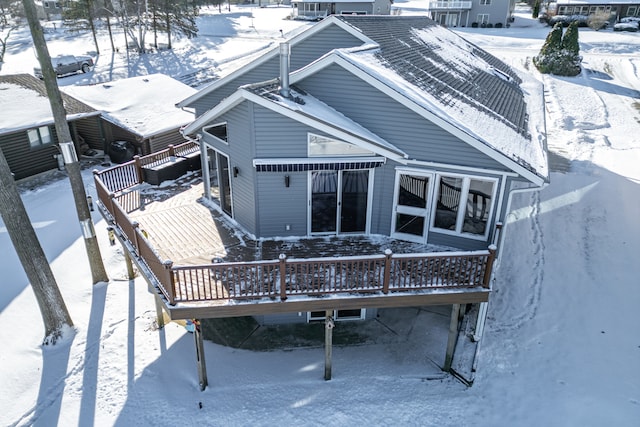 snow covered back of property featuring a deck