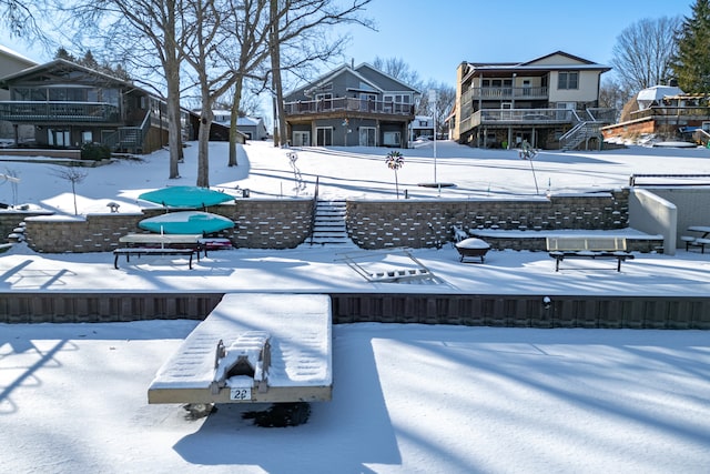 snow covered back of property featuring stairs