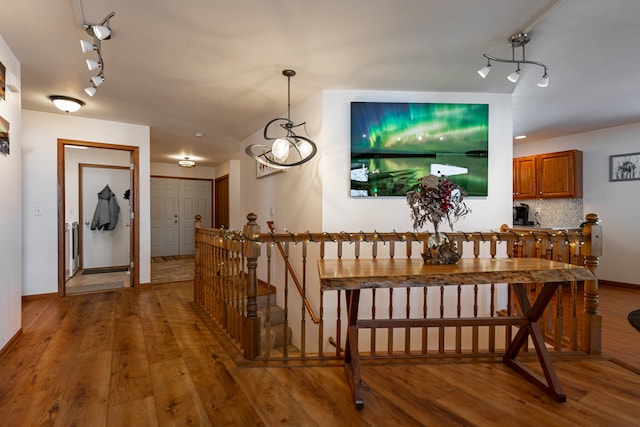 dining space with light wood-type flooring, rail lighting, and baseboards