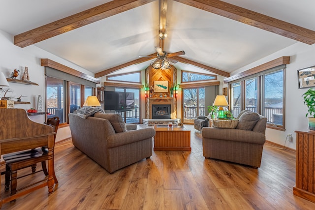 living room with lofted ceiling with beams, light wood-style flooring, baseboards, and a glass covered fireplace