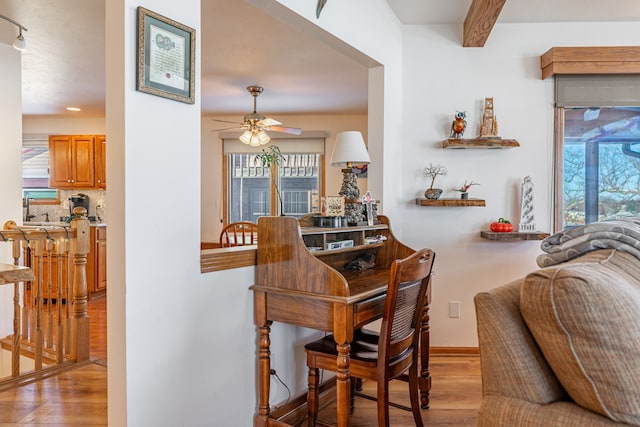 dining area with light wood-style floors, plenty of natural light, beamed ceiling, and a ceiling fan