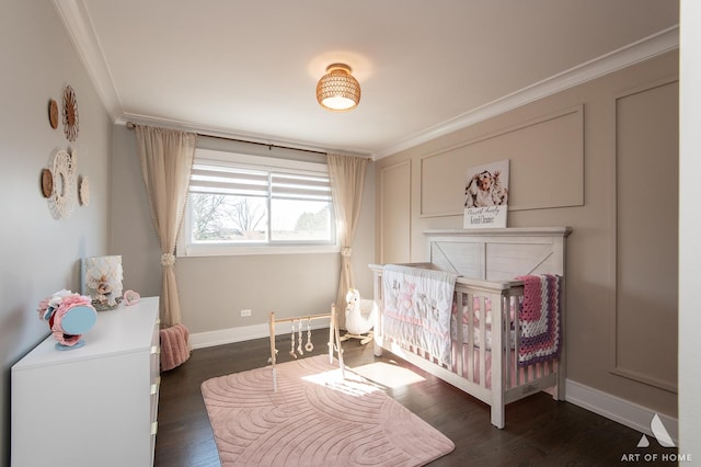 bedroom with a nursery area, wood finished floors, baseboards, and ornamental molding