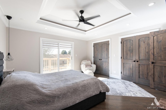 bedroom with access to exterior, multiple closets, a tray ceiling, ornamental molding, and wood finished floors