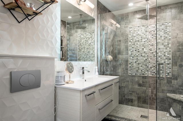 full bath with vanity, a shower stall, tile walls, and decorative backsplash