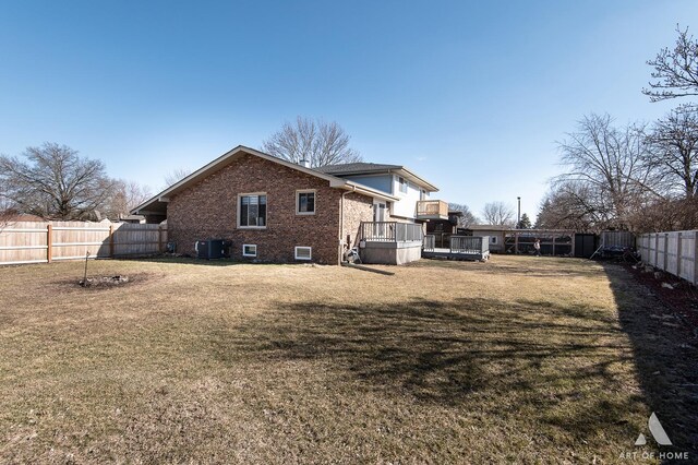 rear view of house featuring central air condition unit, a lawn, a fenced backyard, a wooden deck, and brick siding