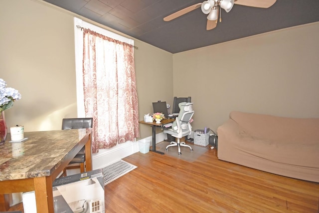 office space featuring visible vents, a healthy amount of sunlight, baseboards, ceiling fan, and wood finished floors