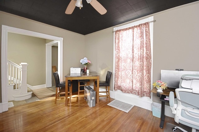 dining area with stairway, baseboards, a ceiling fan, and wood finished floors