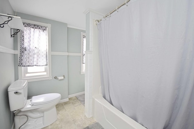 bathroom featuring shower / bath combination with curtain, toilet, and baseboards