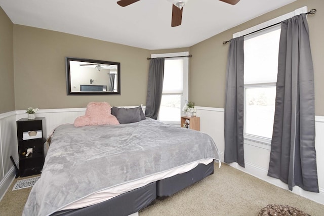 bedroom with a wainscoted wall and ceiling fan