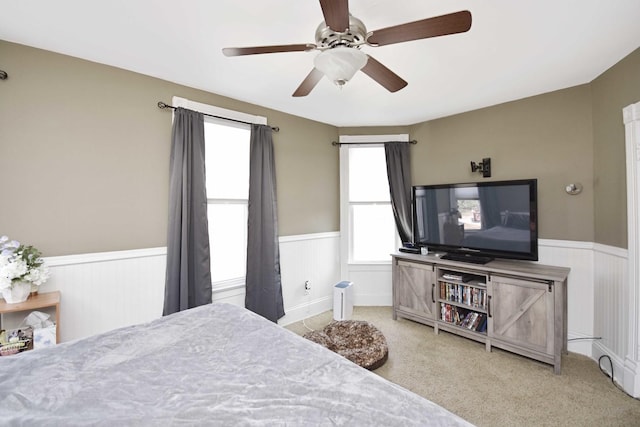 bedroom with a wainscoted wall, carpet flooring, and a ceiling fan