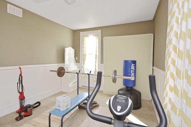 exercise room with visible vents, a wainscoted wall, and a decorative wall