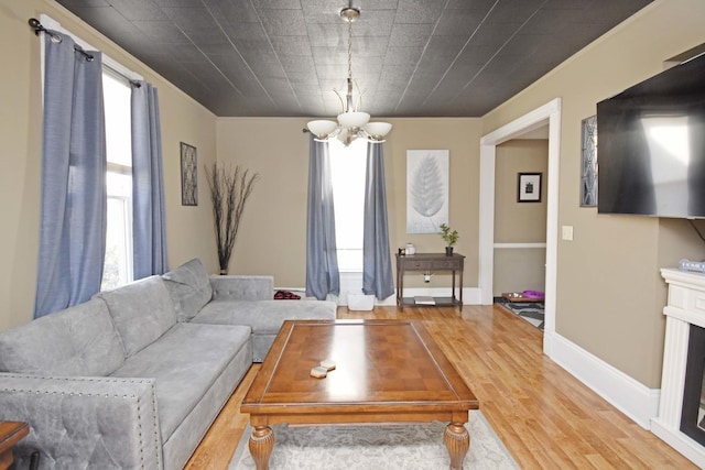 living area featuring a chandelier, baseboards, and wood finished floors