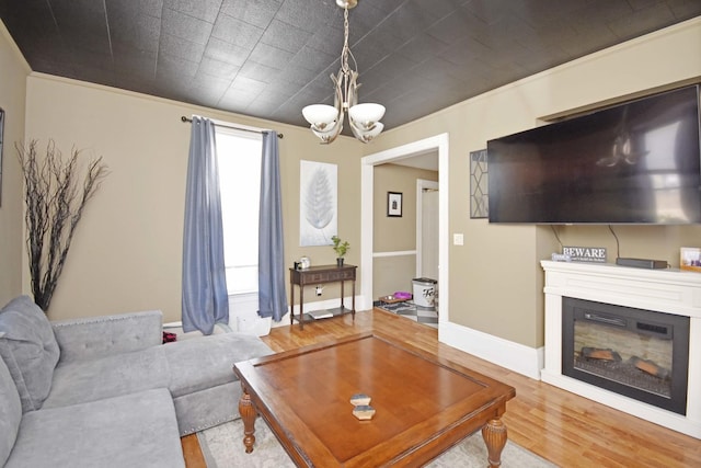 living area with a glass covered fireplace, crown molding, wood finished floors, and baseboards