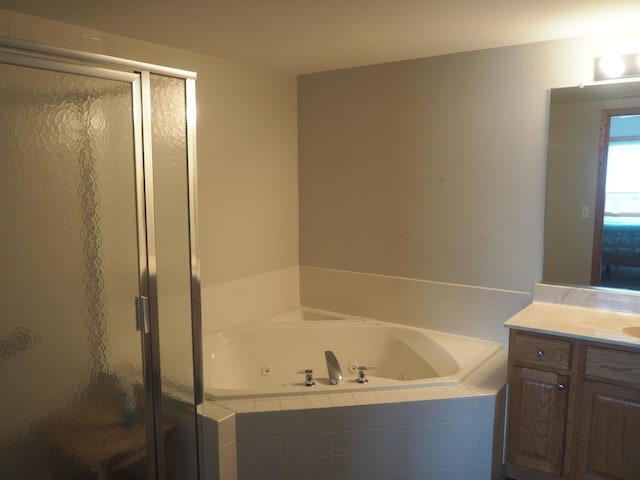 full bath with a stall shower, vanity, and a whirlpool tub