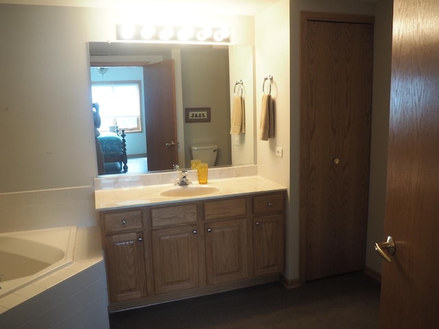 bathroom featuring tiled bath, vanity, and toilet