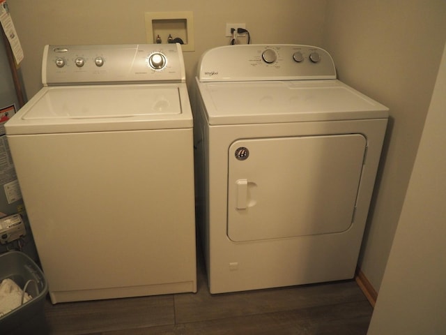 clothes washing area with dark wood-style floors, washing machine and dryer, and laundry area