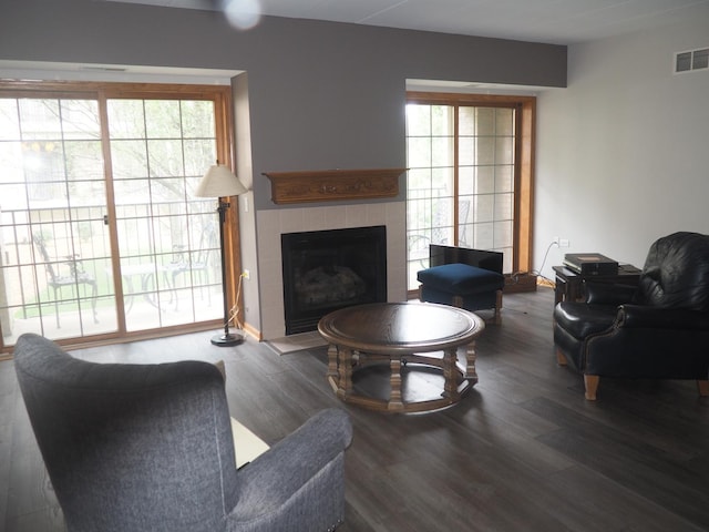 living room with visible vents, wood finished floors, and a tile fireplace