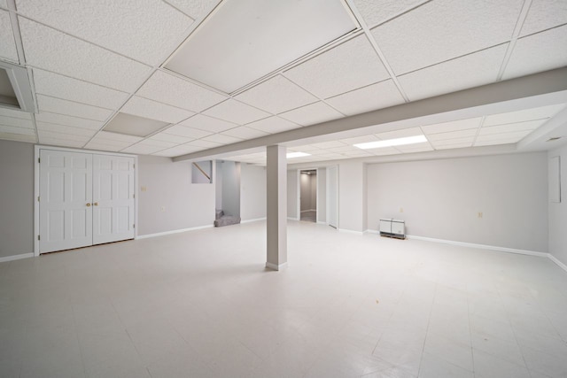 finished basement featuring a drop ceiling, tile patterned floors, and baseboards