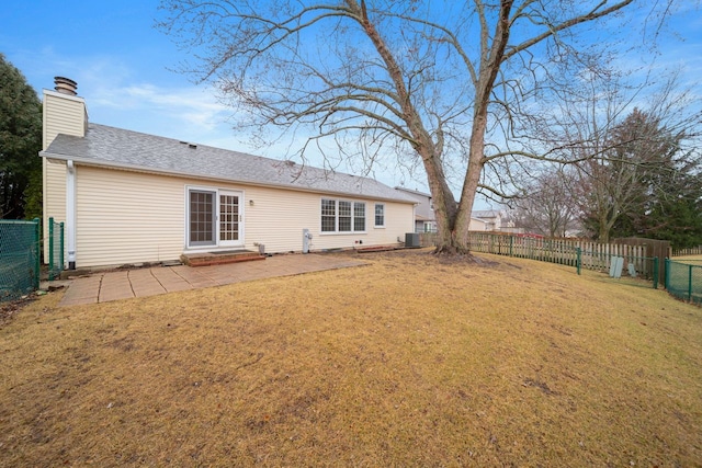 rear view of property with a yard, a chimney, a patio, central AC, and a fenced backyard