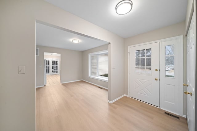 foyer with light wood finished floors, visible vents, and baseboards