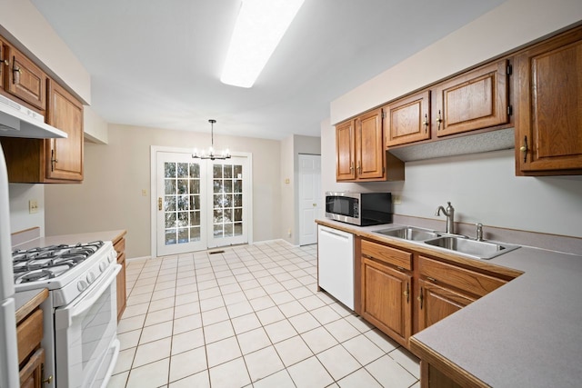 kitchen featuring white appliances, brown cabinets, an inviting chandelier, a sink, and light tile patterned flooring