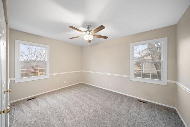 empty room with a wealth of natural light, carpet flooring, and visible vents