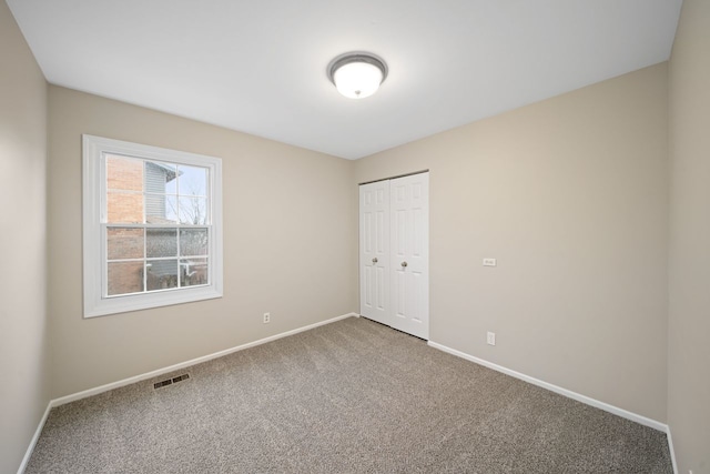 unfurnished bedroom with carpet floors, baseboards, visible vents, and a closet