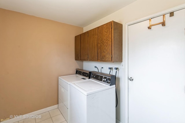 washroom featuring washer and dryer, baseboards, cabinet space, and light tile patterned floors