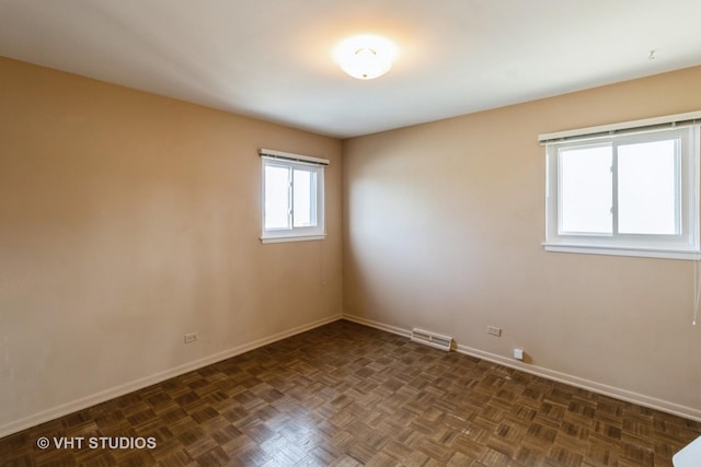 unfurnished room with baseboards and visible vents