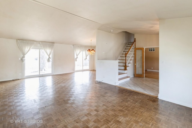 unfurnished living room with visible vents, lofted ceiling, stairway, baseboards, and a chandelier