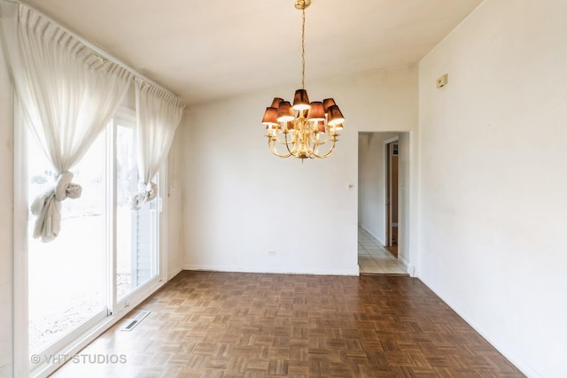 empty room with a notable chandelier, baseboards, and visible vents