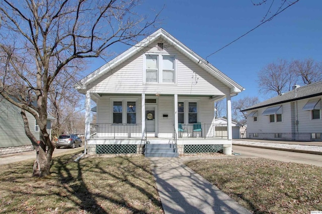 bungalow-style home with a porch, a front yard, and driveway