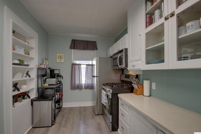 kitchen featuring light wood finished floors, open shelves, light countertops, appliances with stainless steel finishes, and white cabinets