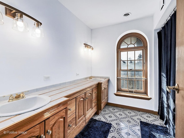 full bath featuring visible vents, a sink, baseboards, and double vanity