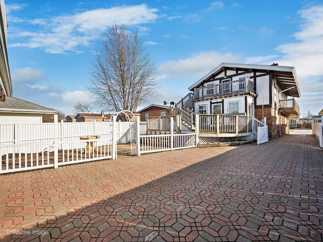 view of front of home featuring a balcony, fence, and a patio