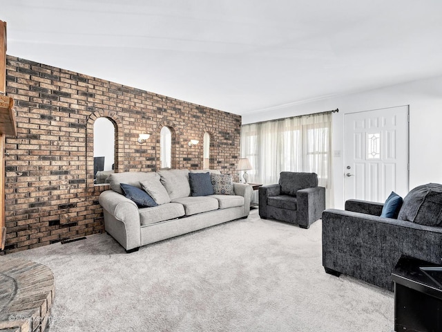 carpeted living area featuring brick wall