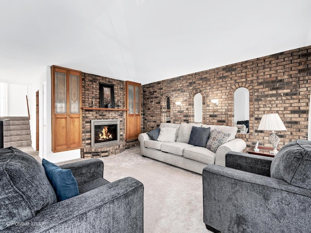 living area with carpet floors, a fireplace, brick wall, and stairs