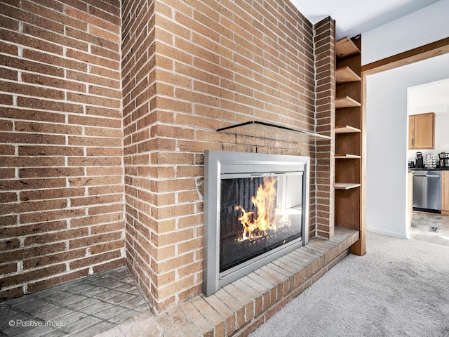 room details featuring stainless steel dishwasher, carpet, and a brick fireplace