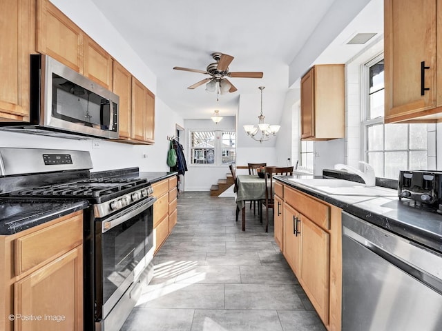 kitchen featuring light tile patterned floors, ceiling fan with notable chandelier, stainless steel appliances, a sink, and decorative light fixtures